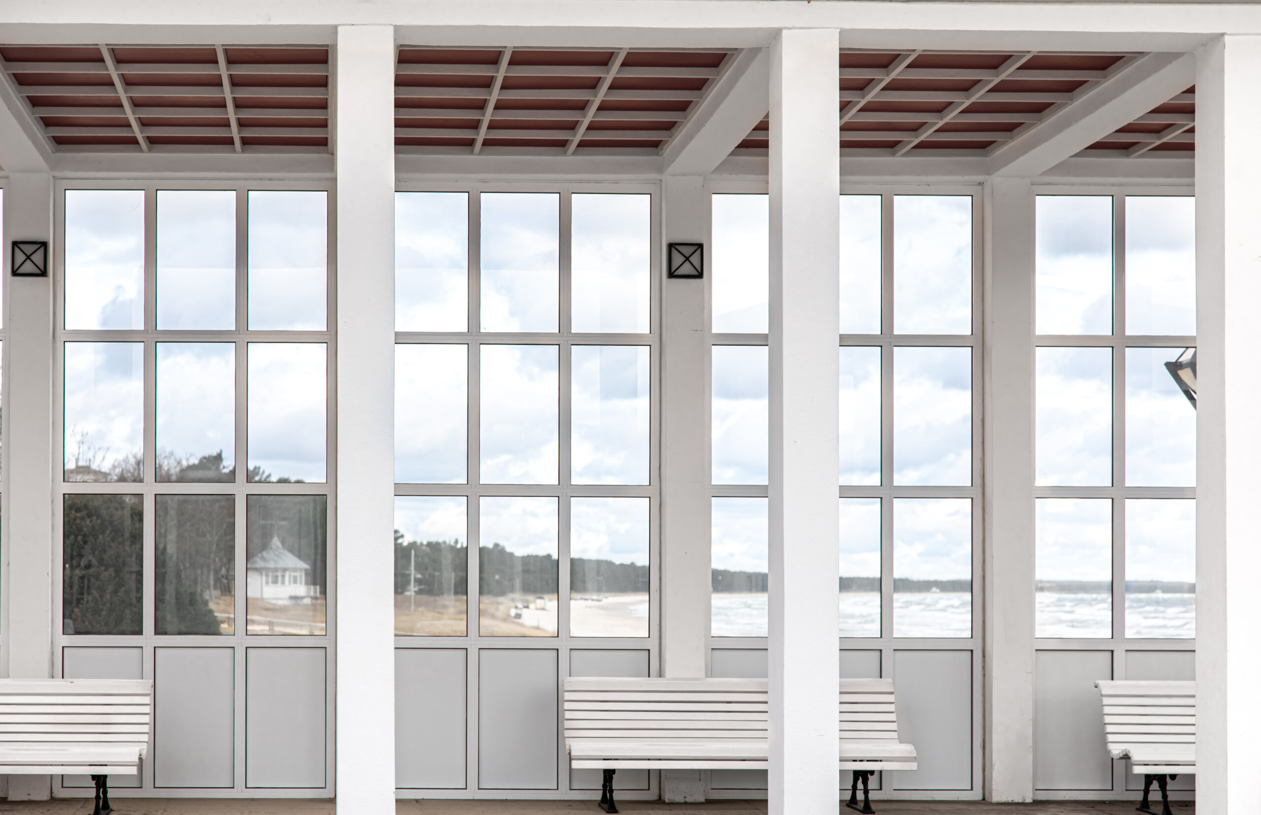 Exterior of a white building with benches overlooking the sea.