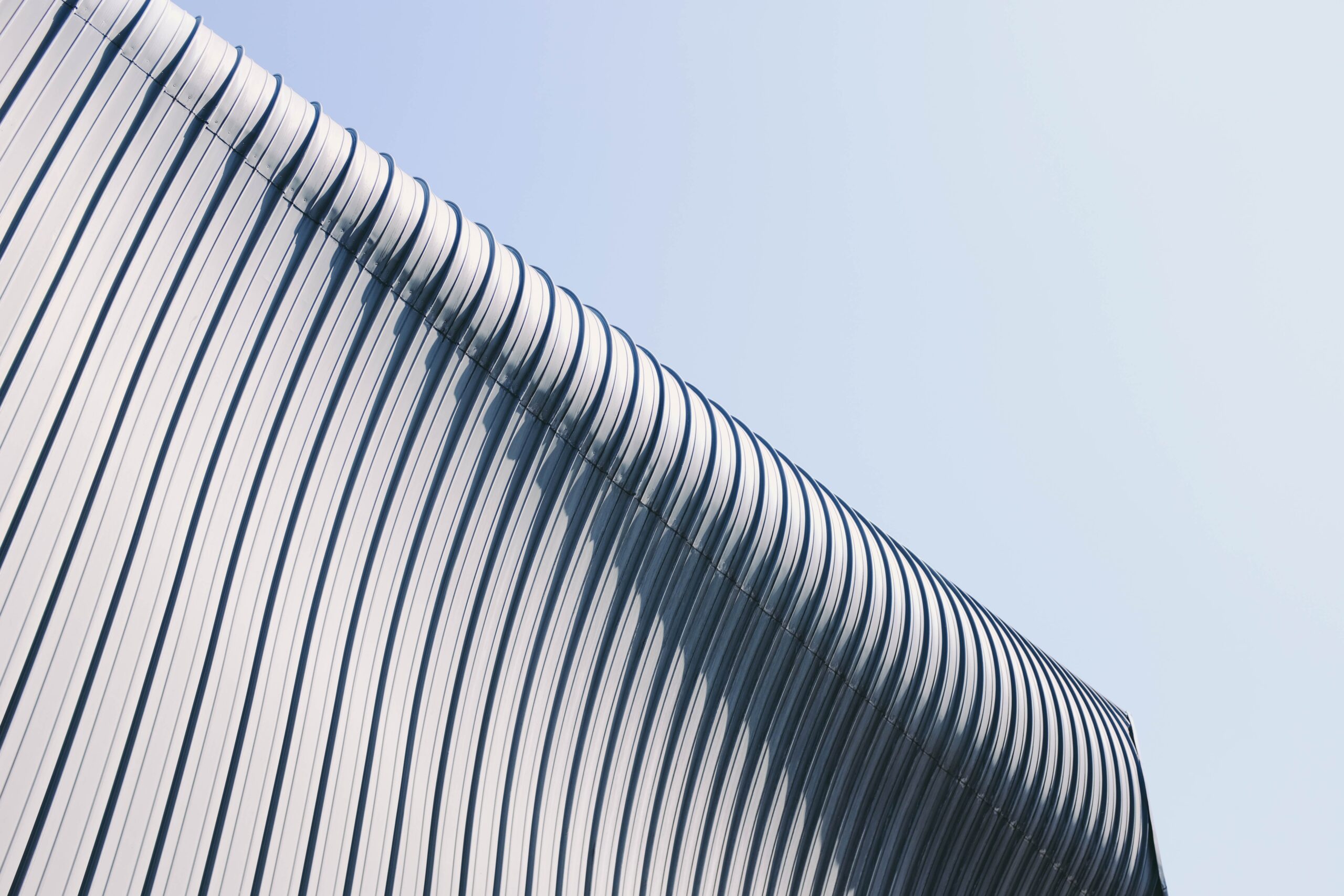 A low angle shot of a grey and white building roof with interesting textures under the blue sky